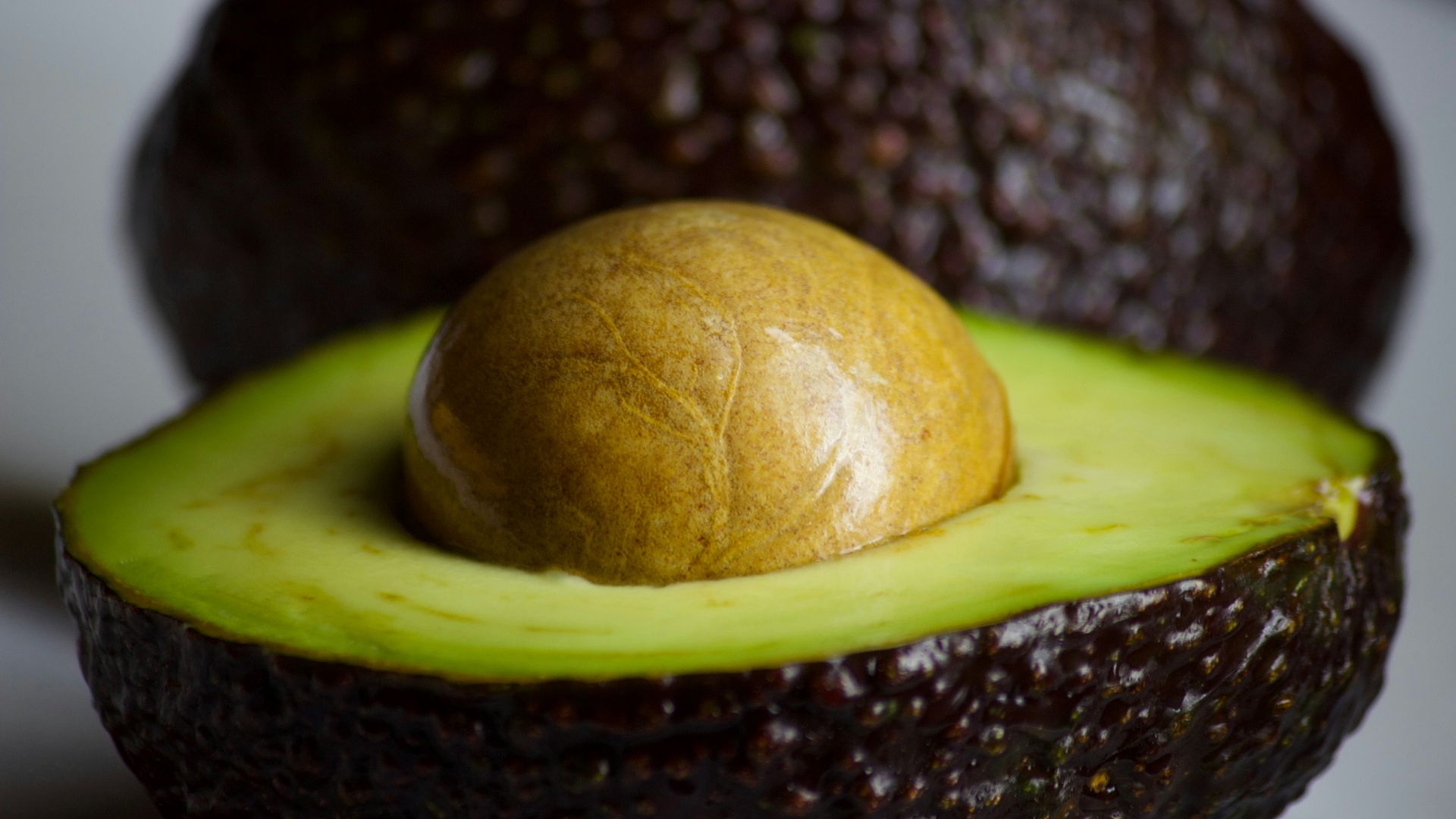 An avocado cut in half with a whole avocado in the middle