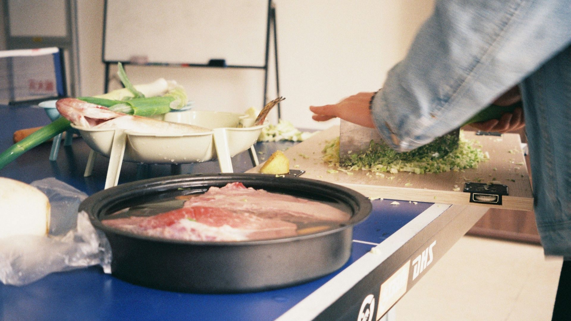 Raw meat soaking in water on a blue surface.
