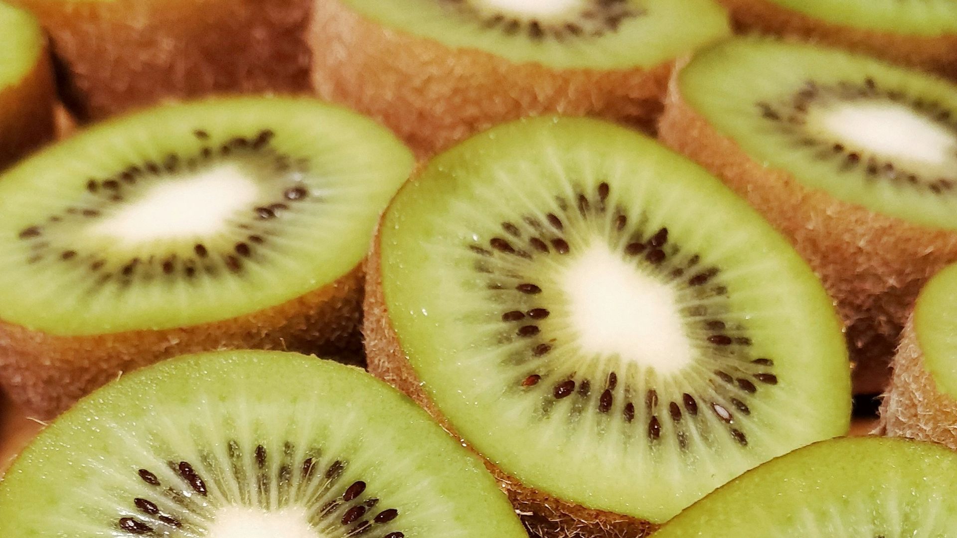 a bunch of kiwi cut in half on a cutting board