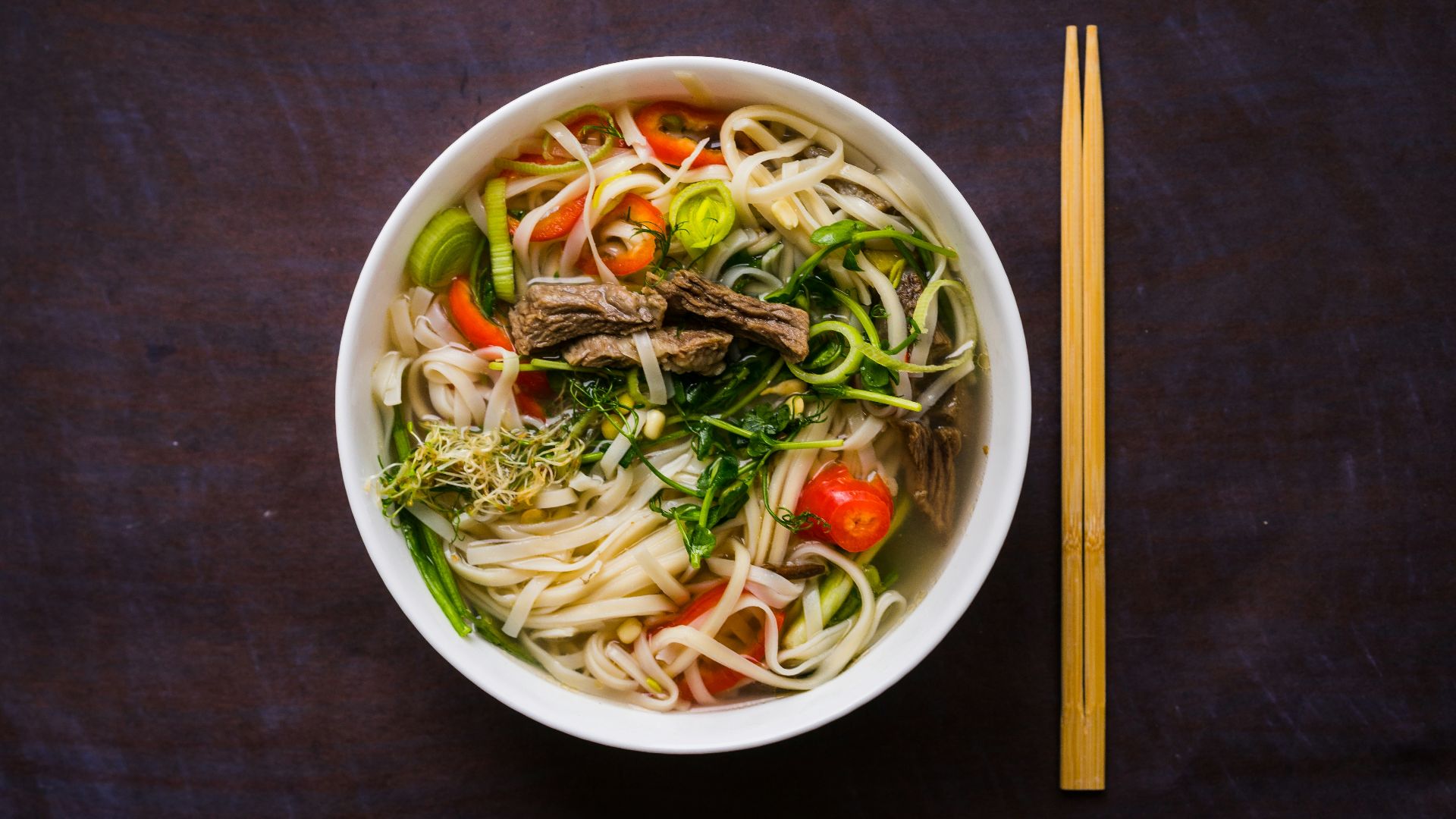 a bowl of noodle soup with chopsticks on the side