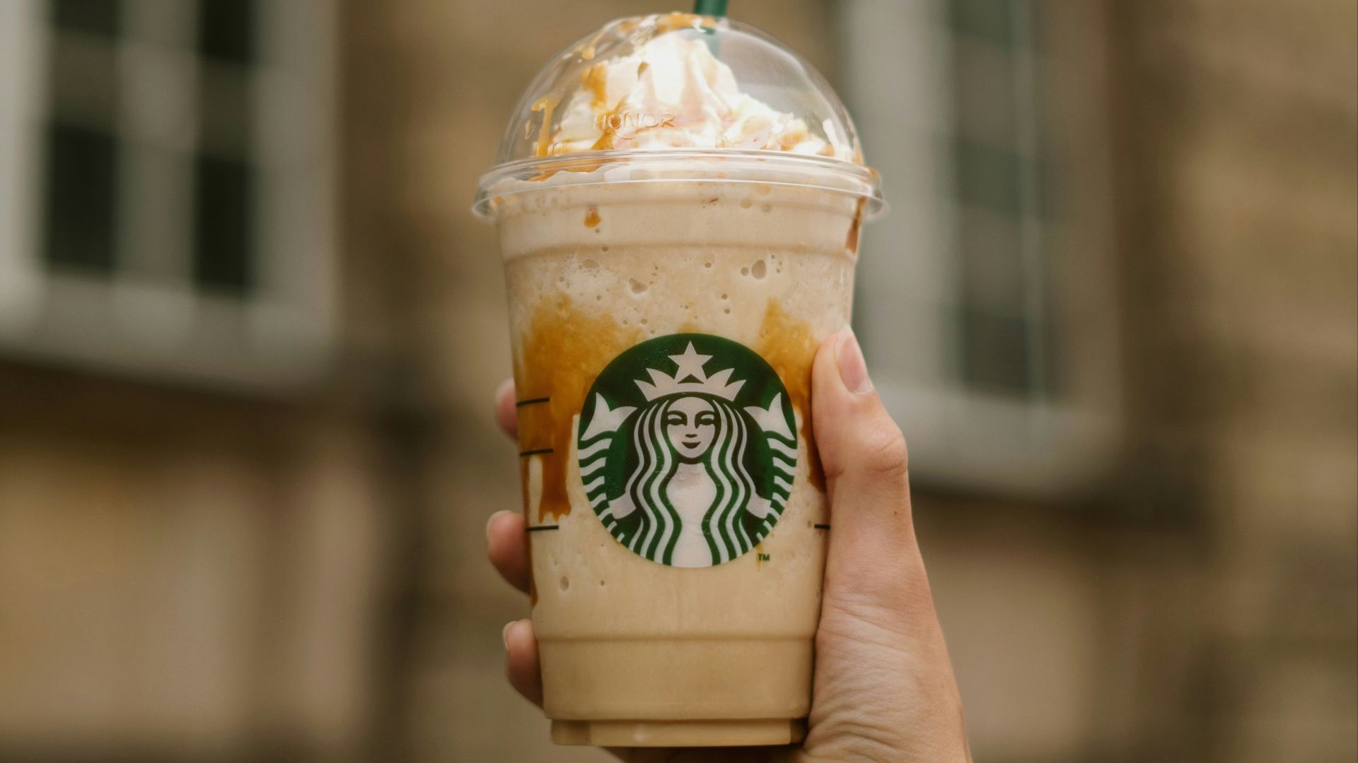 a hand holding a cup of ice cream with a straw
