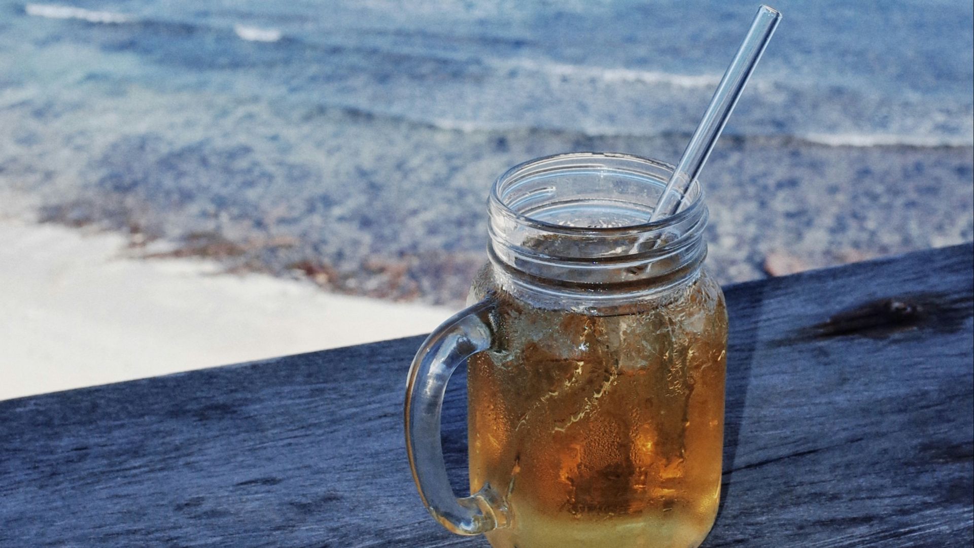 A mason jar filled with liquid sitting on top of a wooden bench