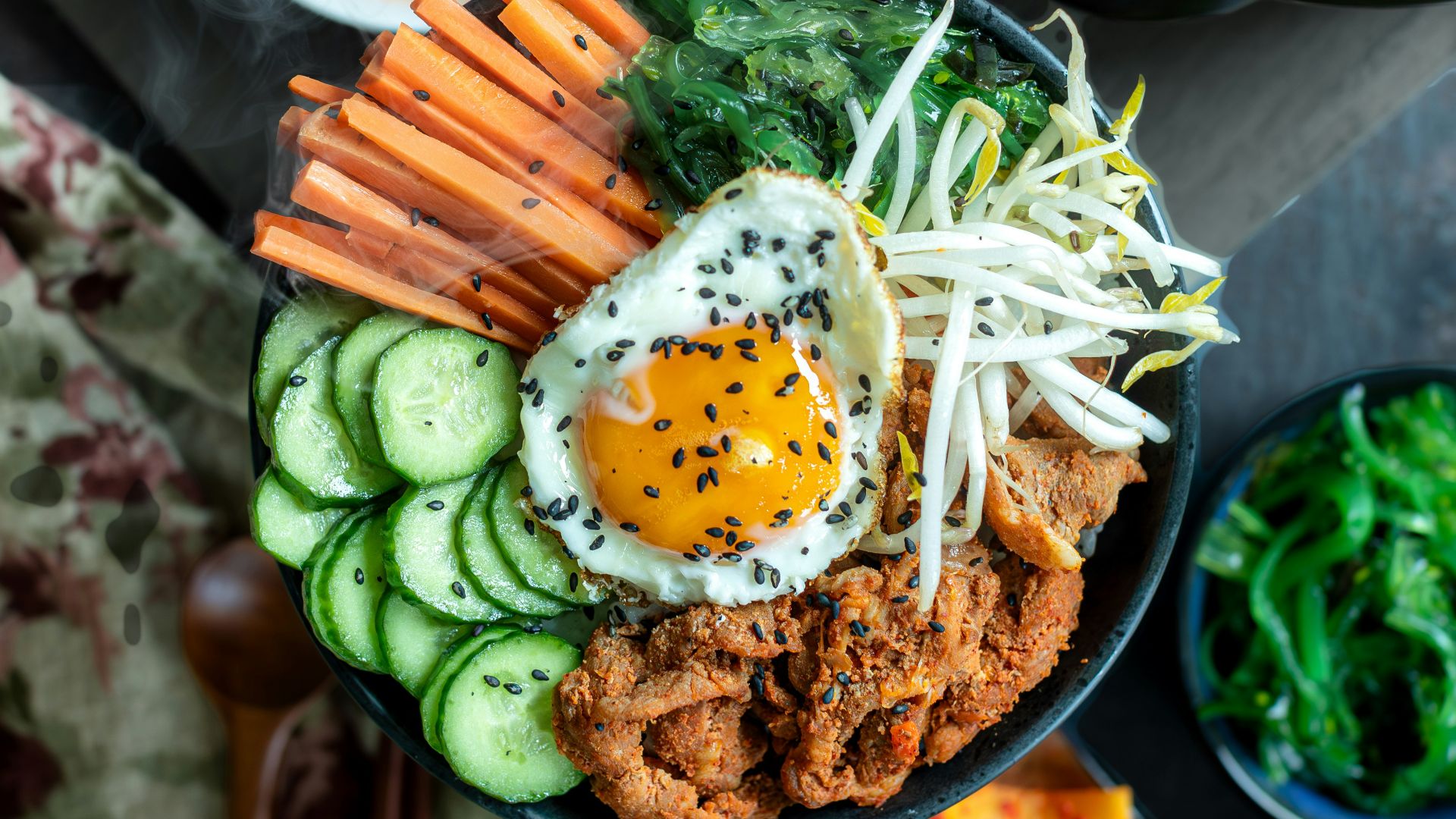 A bowl of food with carrots, cucumbers and other vegetables