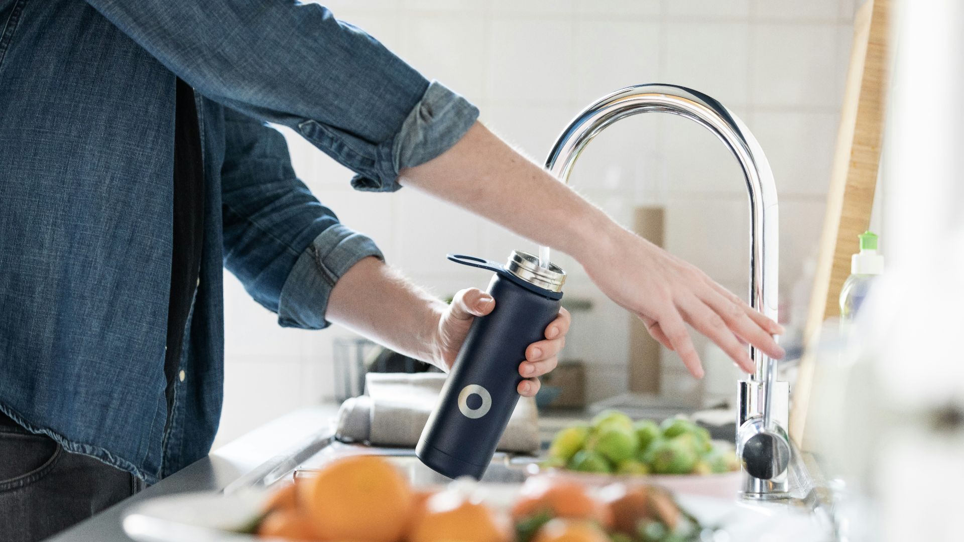 person in blue denim jacket holding stainless steel bottle