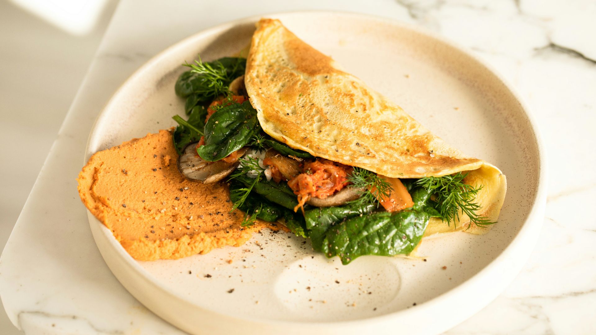 a white plate topped with an omelet and greens