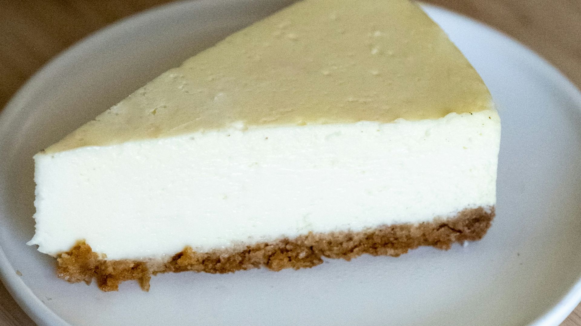 a piece of cheesecake on a plate next to a cup of tea