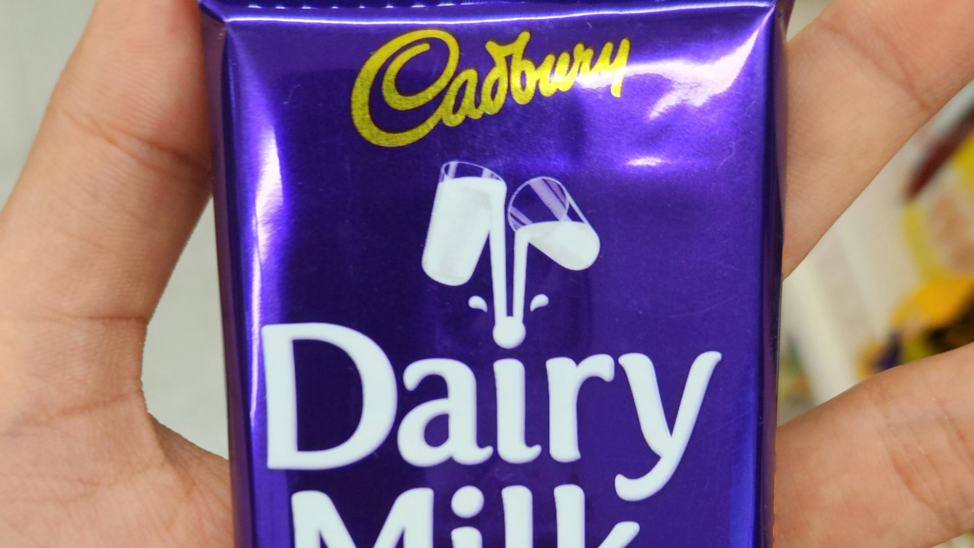 A cadbury dairy milk chocolate bar is held.