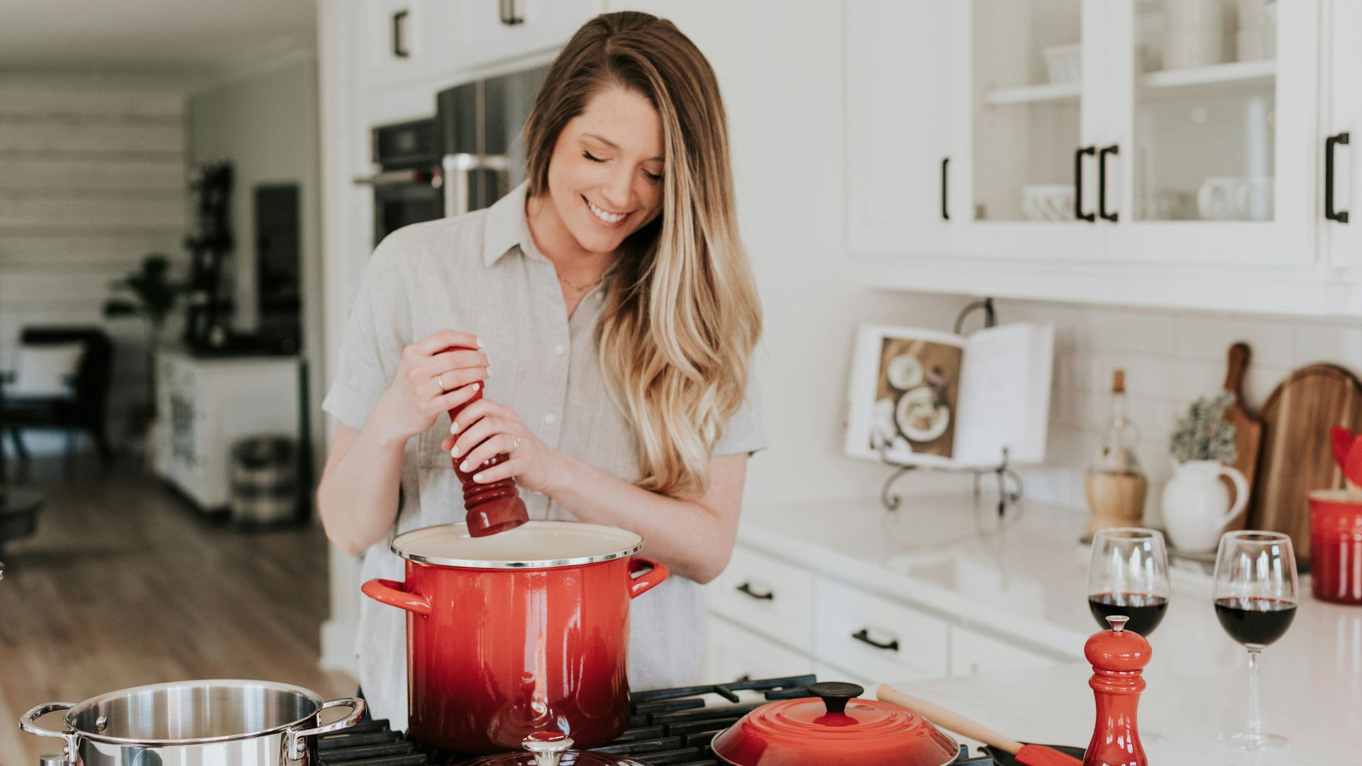 smiling woman standing and putting pepper on stock pot