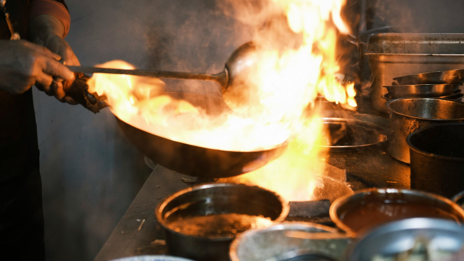 a person cooking food in a wok on a stove