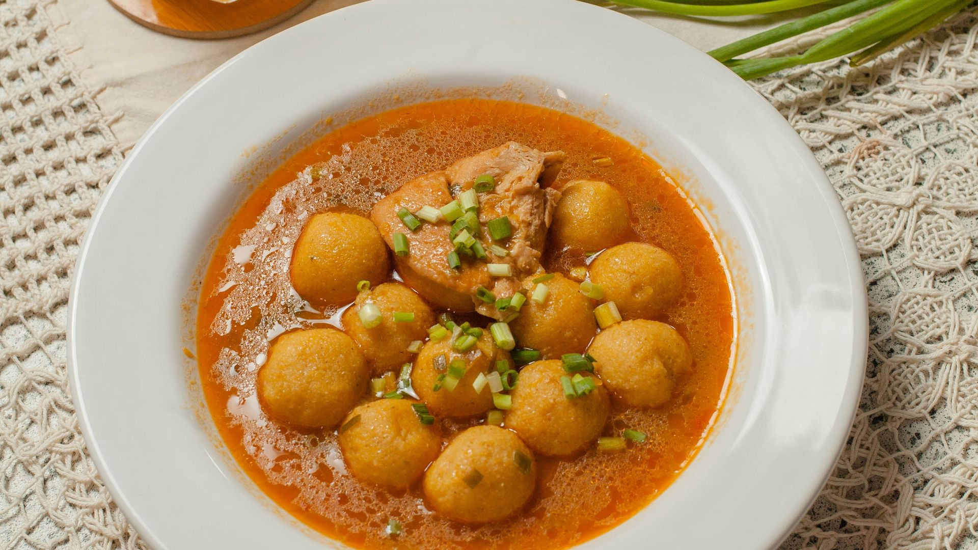 A bowl of soup next to a bowl of bread and a glass of orange juice