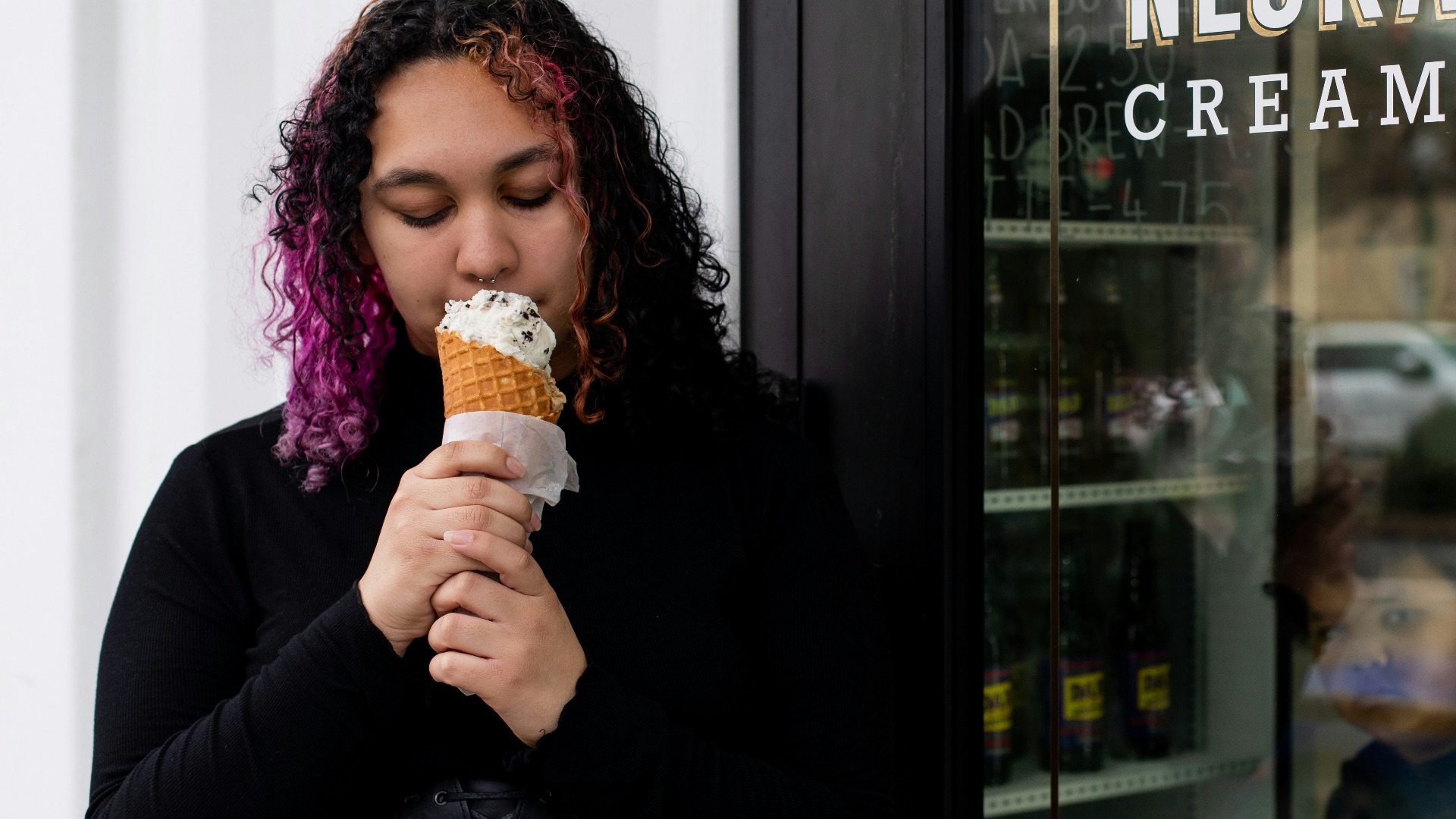 a woman eating an ice cream cone in front of a store