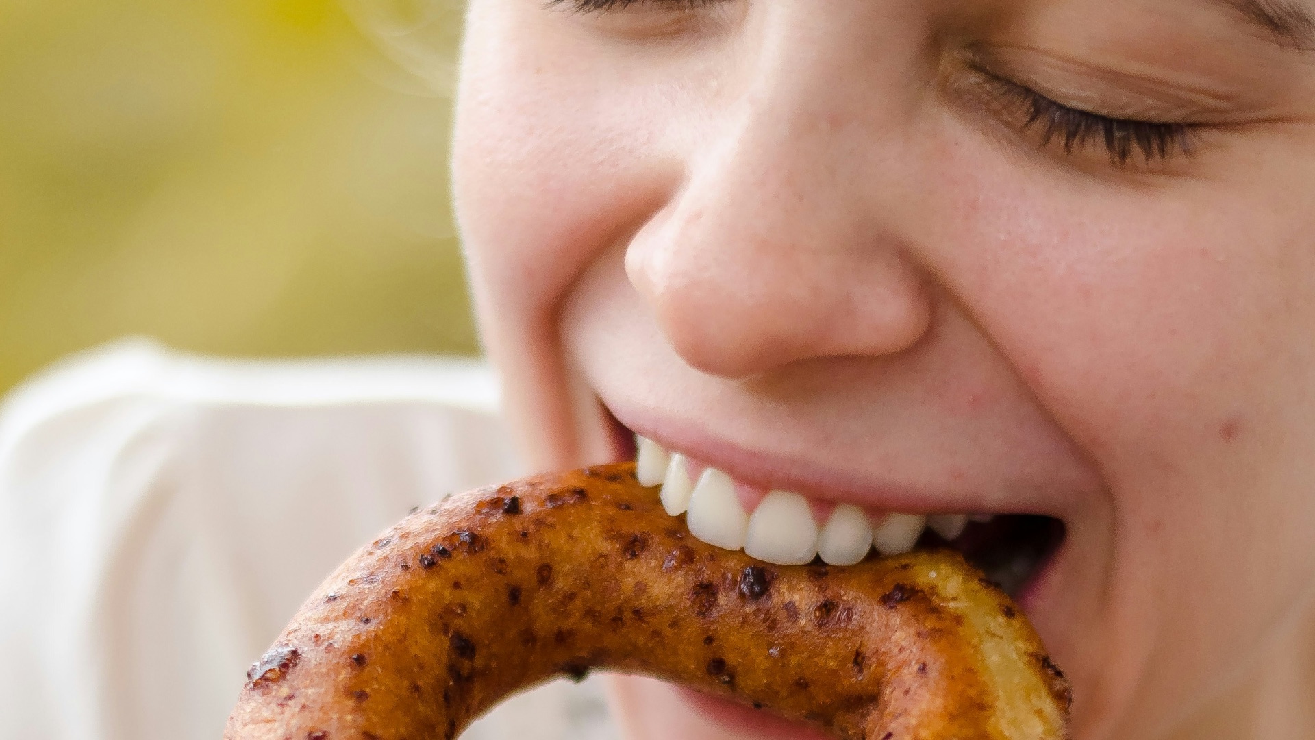 person holding brown doughnut with white cream
