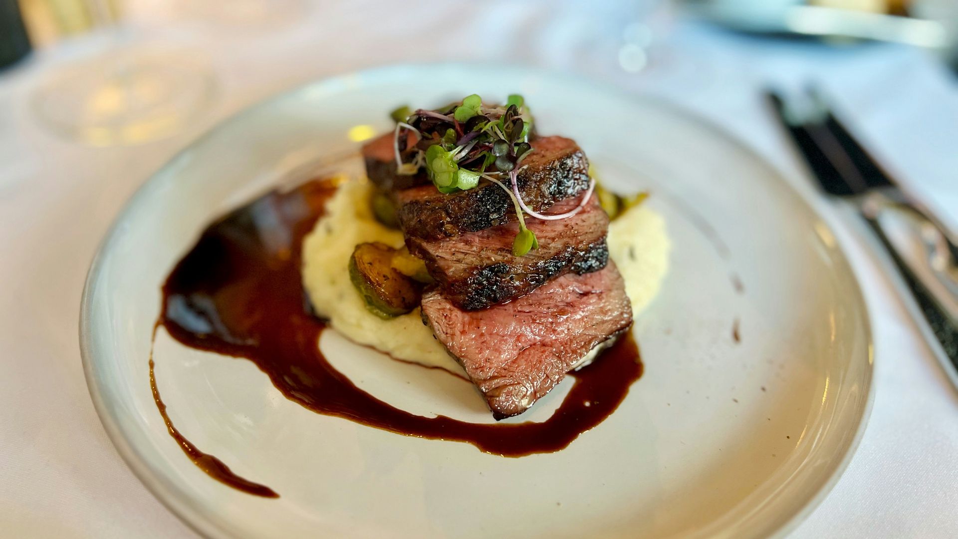 A white plate topped with a piece of meat covered in sauce
