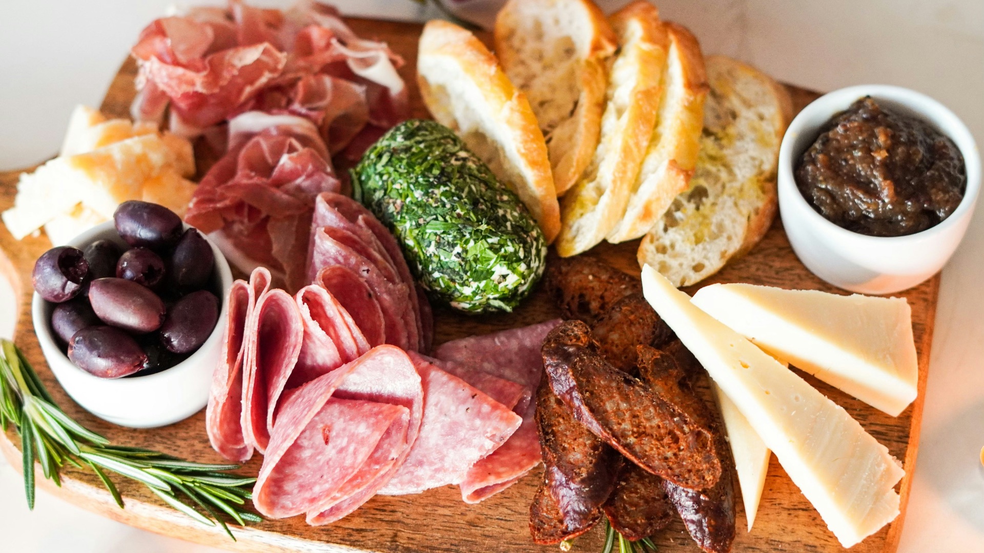 sliced meat with vegetable and bread on brown wooden chopping board