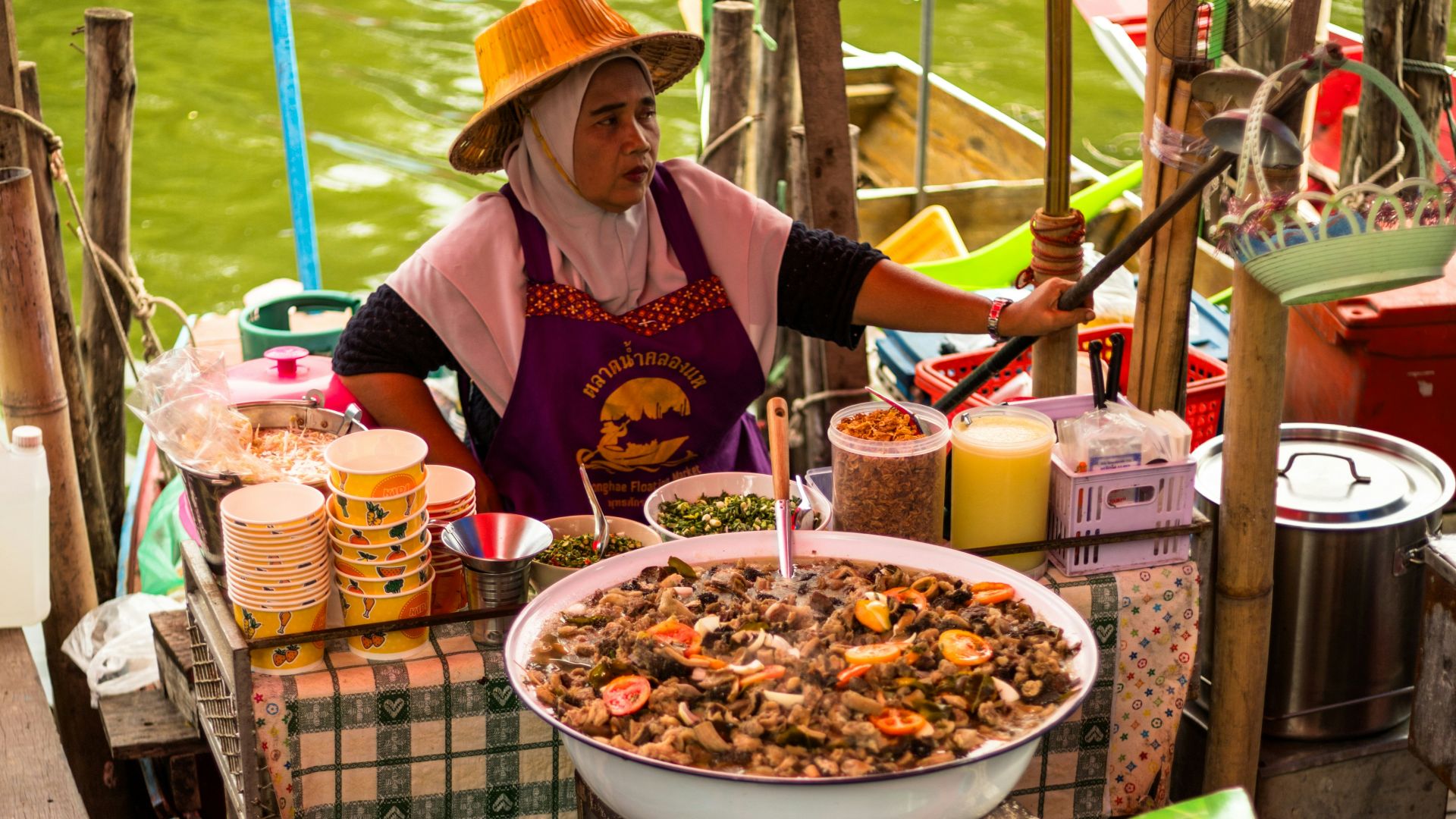Woman sells food from a boat in thailand.