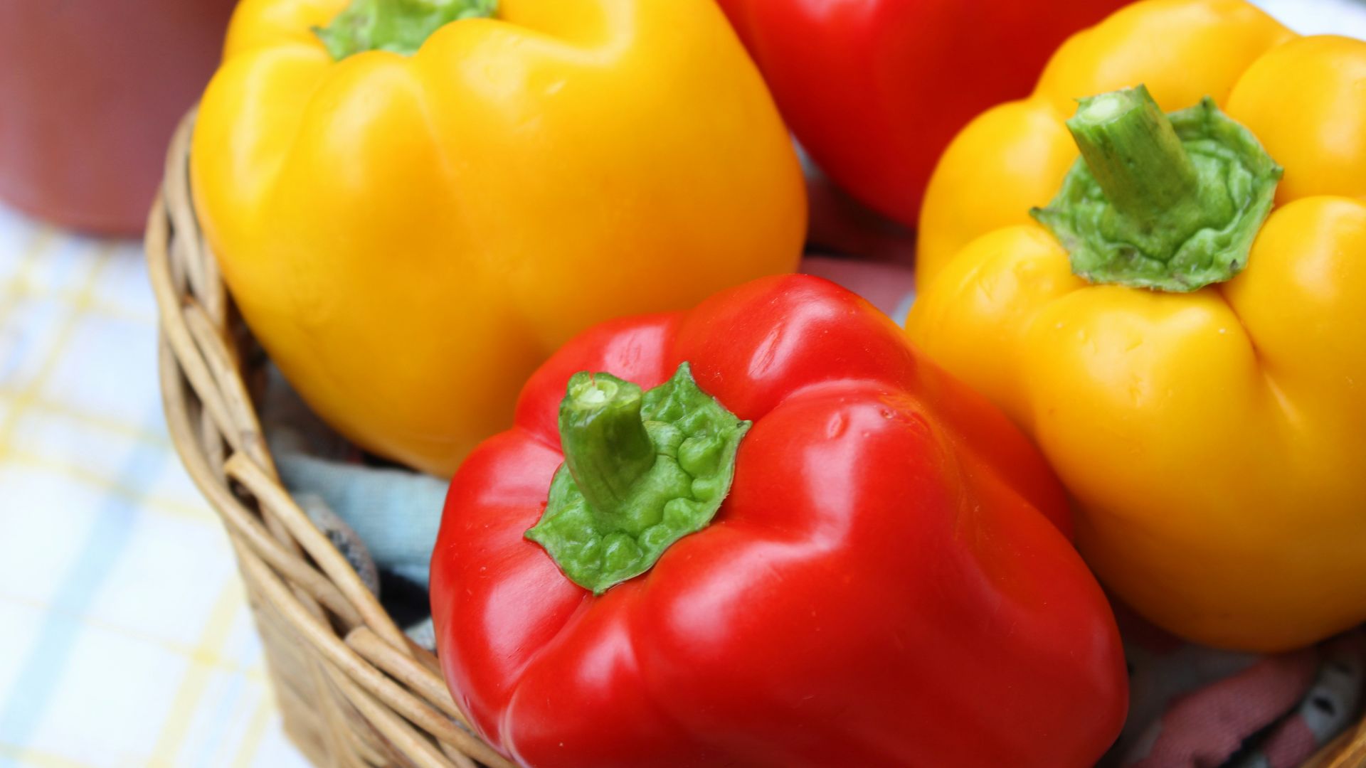 red and yellow bell peppers in brown woven basket