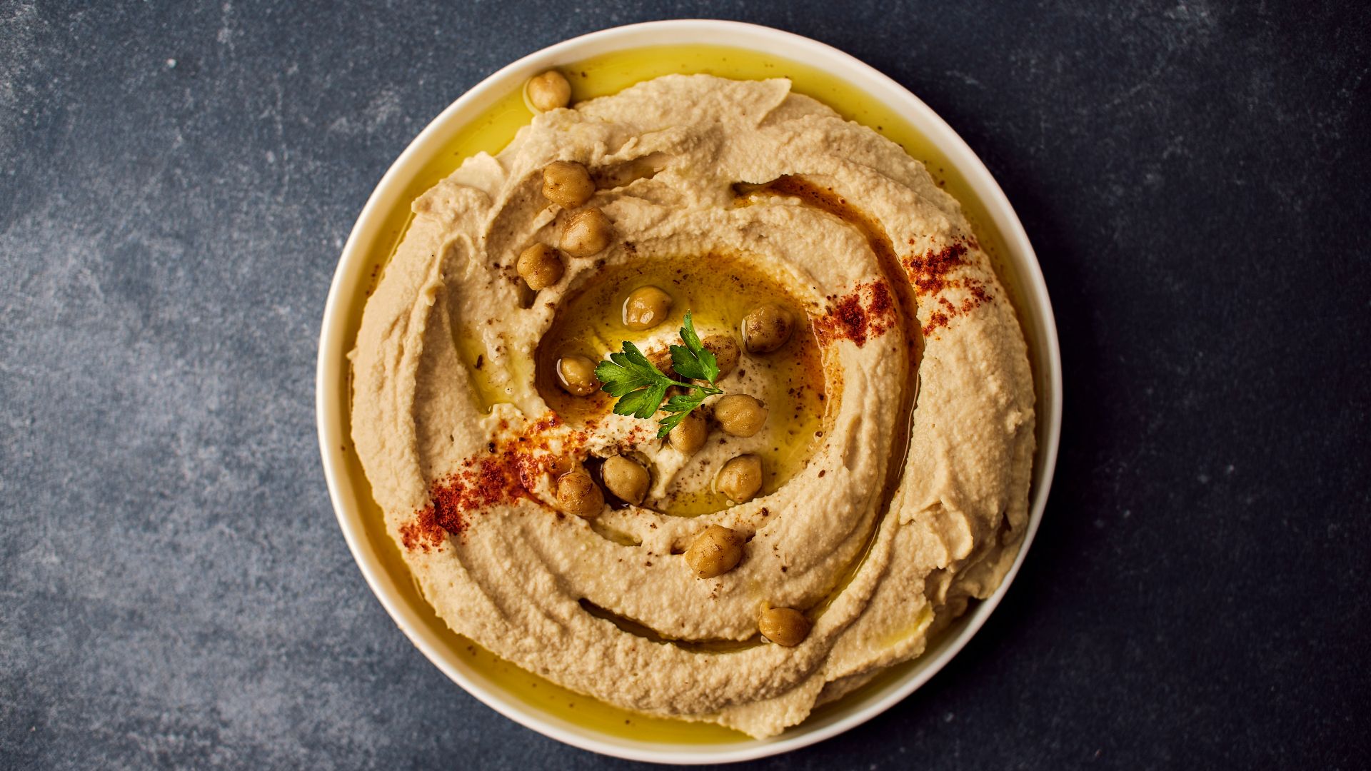 a bowl of hummus with a garnish on top