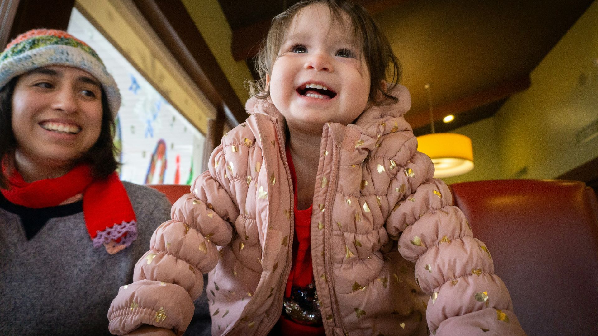 a little girl sitting next to a woman at a table