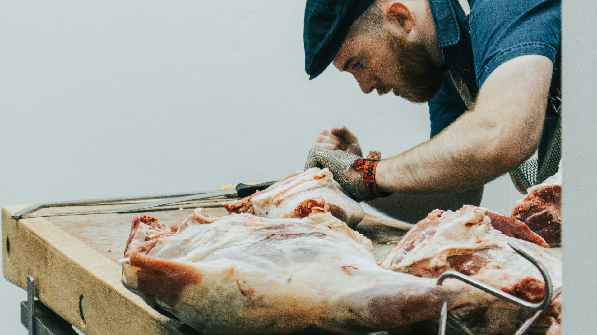 man in blue shirt slicing meat