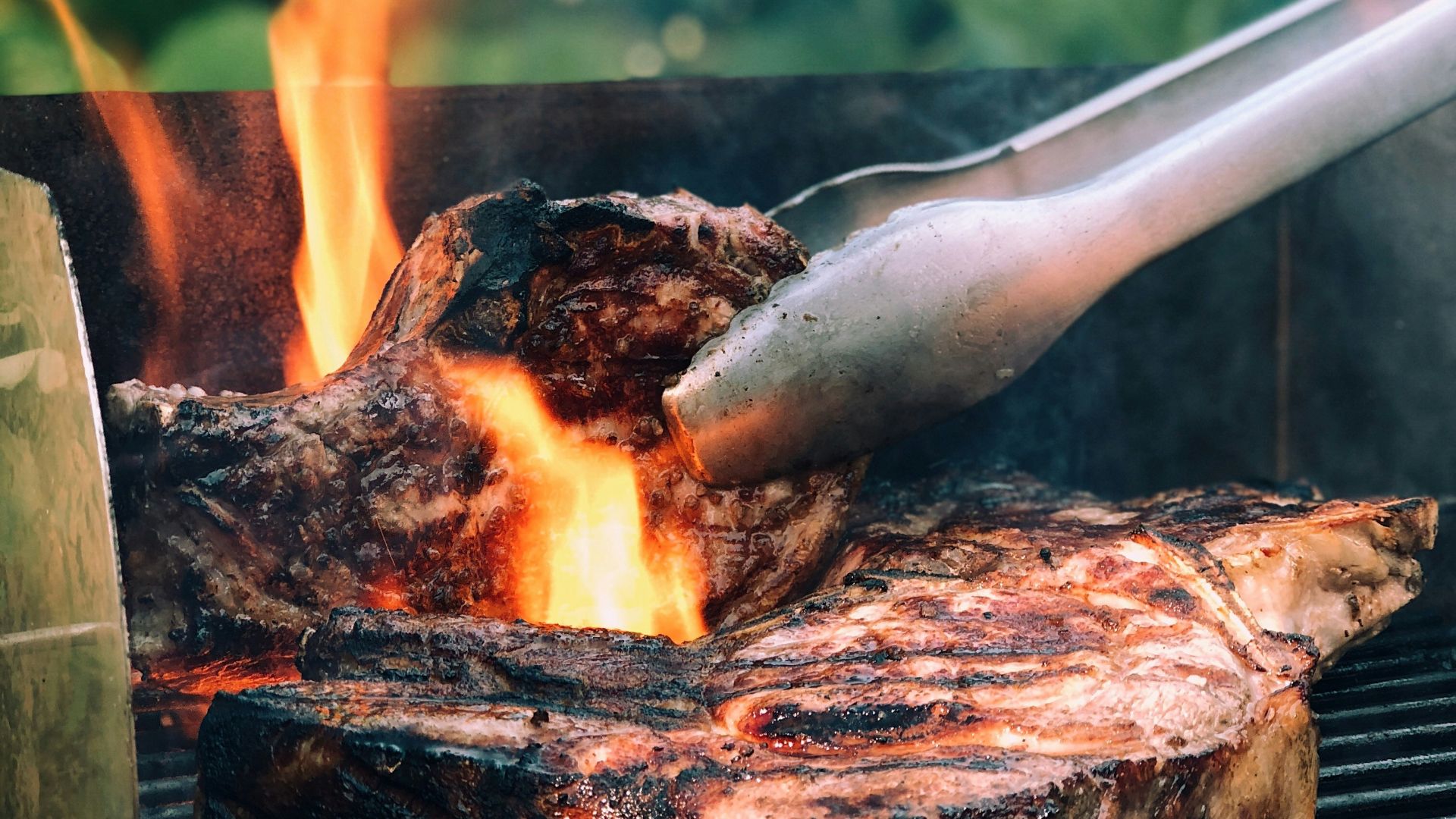 gray metal tong and grilled meat with fire