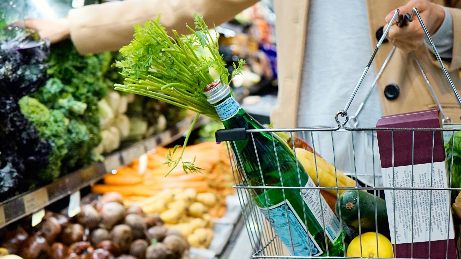 woman in white coat holding green shopping cart