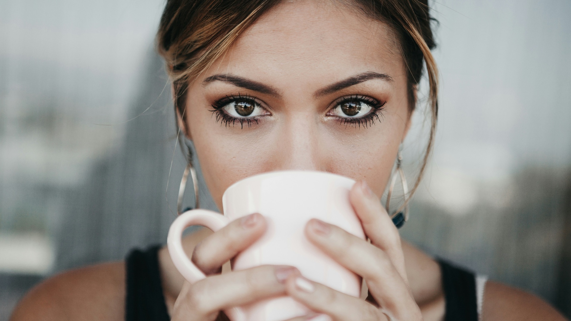 woman drinking from white coffee cup