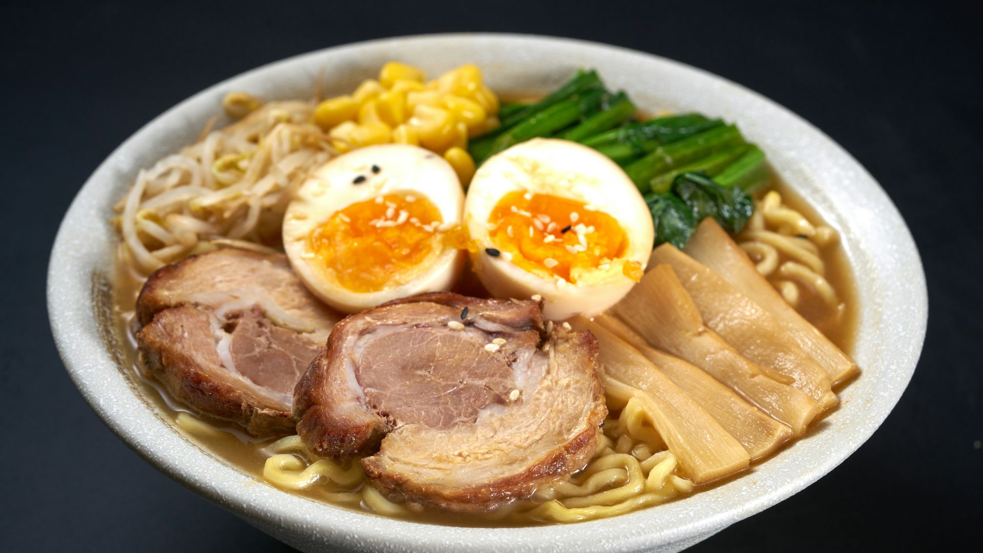 a bowl of ramen with meat, eggs, noodles and vegetables
