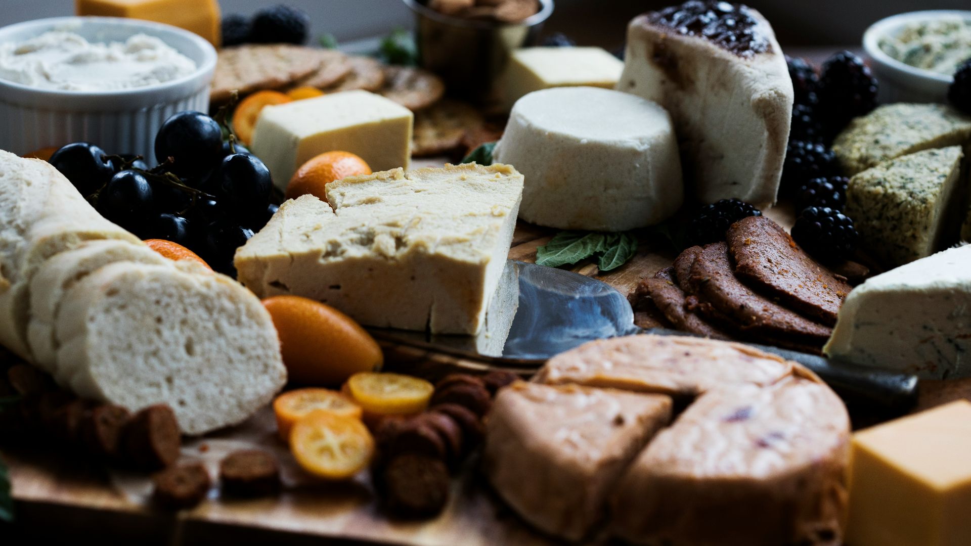 a wooden cutting board topped with lots of different types of cheese