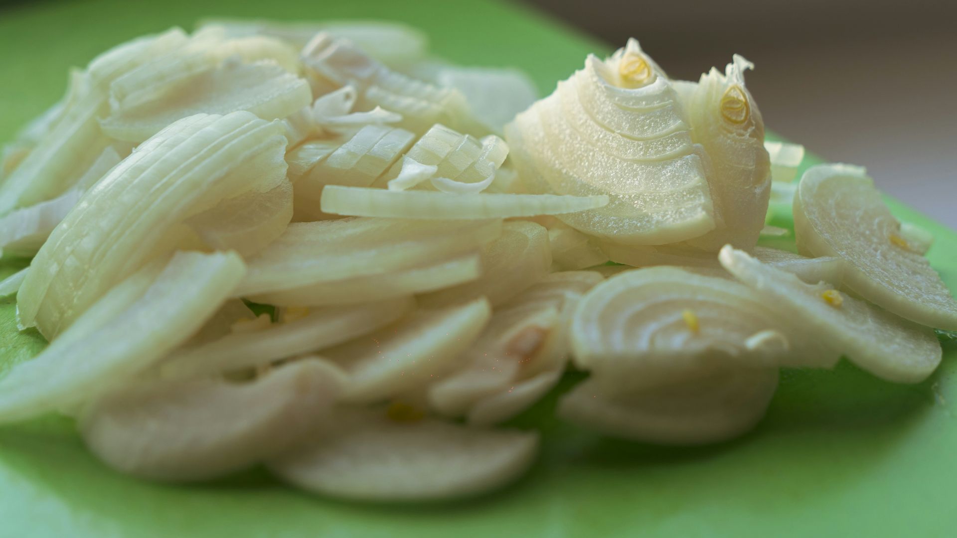 Sliced onions on a green cutting board