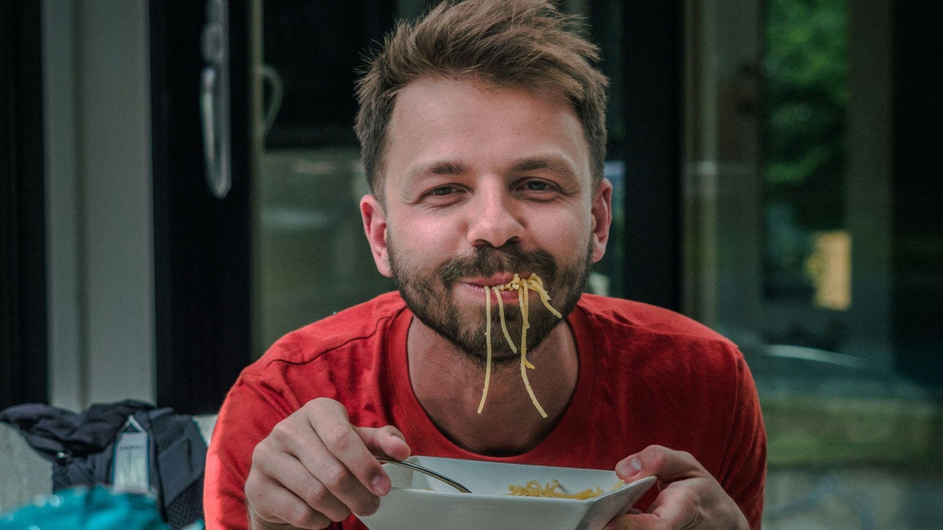 man in red crew neck t-shirt holding white and red labeled can