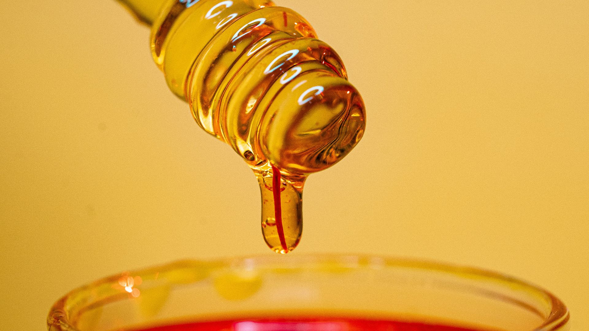 clear glass bottle pouring red liquid on clear drinking glass
