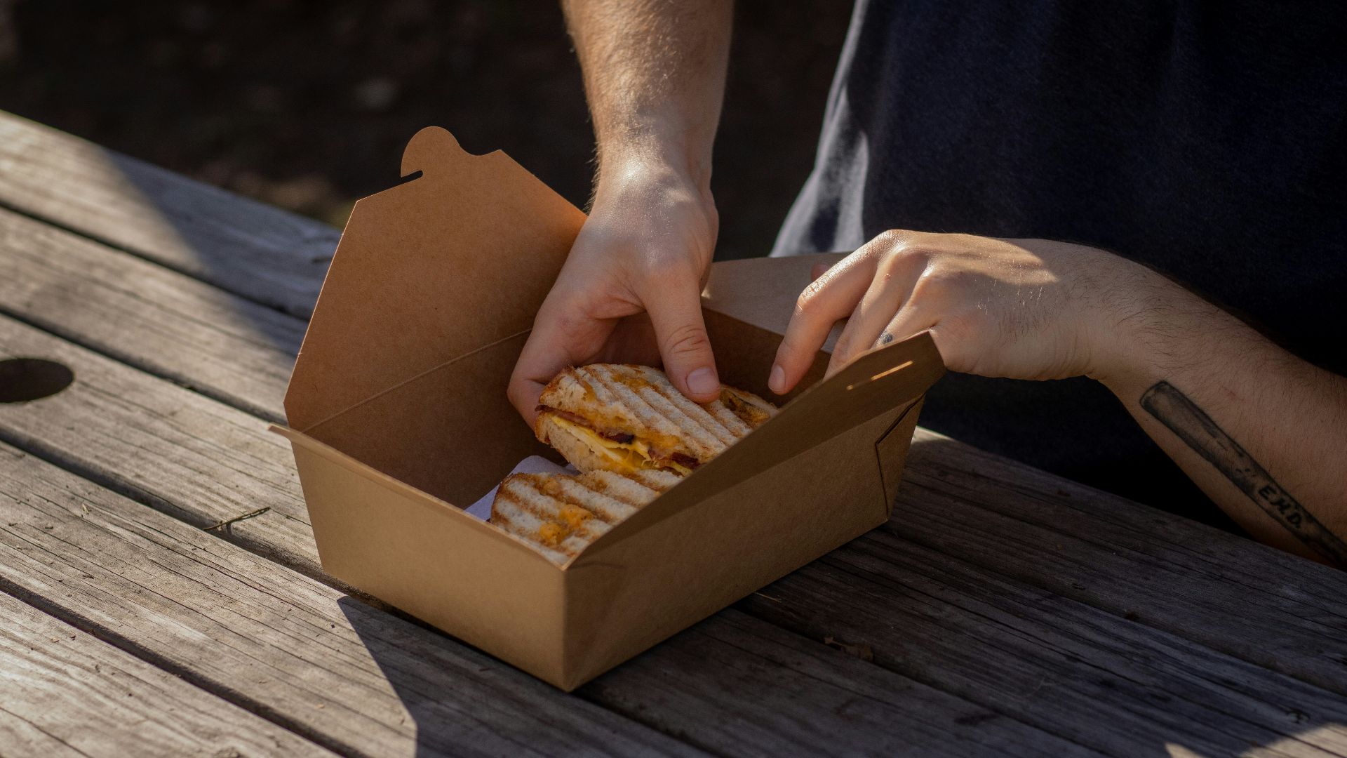 person holding brown box with brown and white food