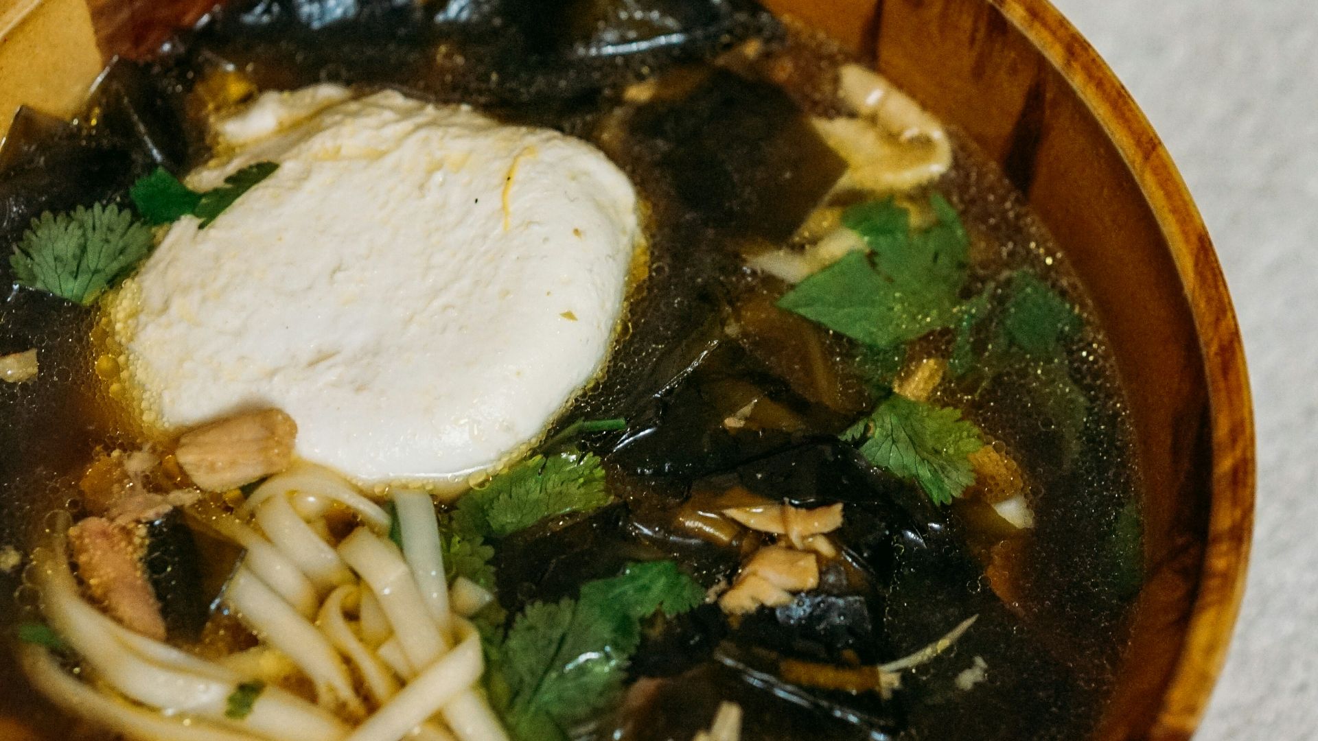 person holding brown ceramic bowl with soup
