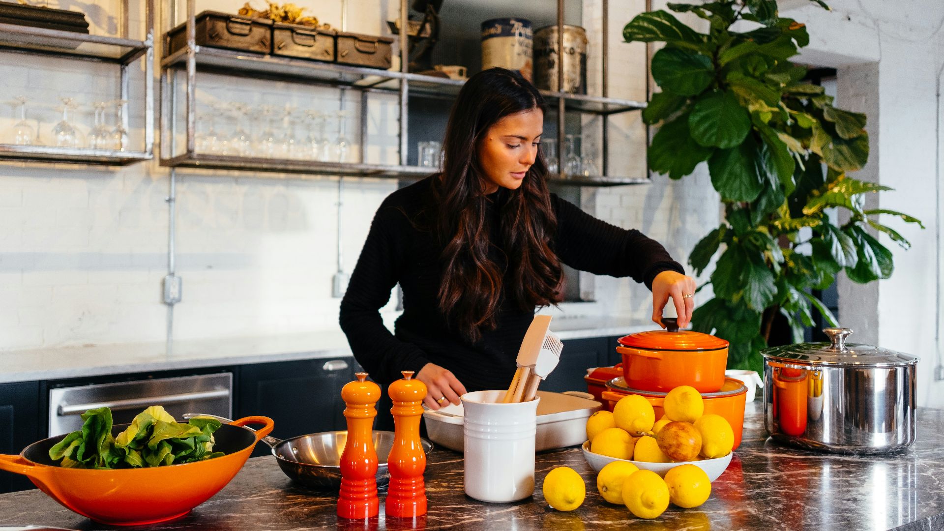 woman standing in front of fruits holding pot's lid