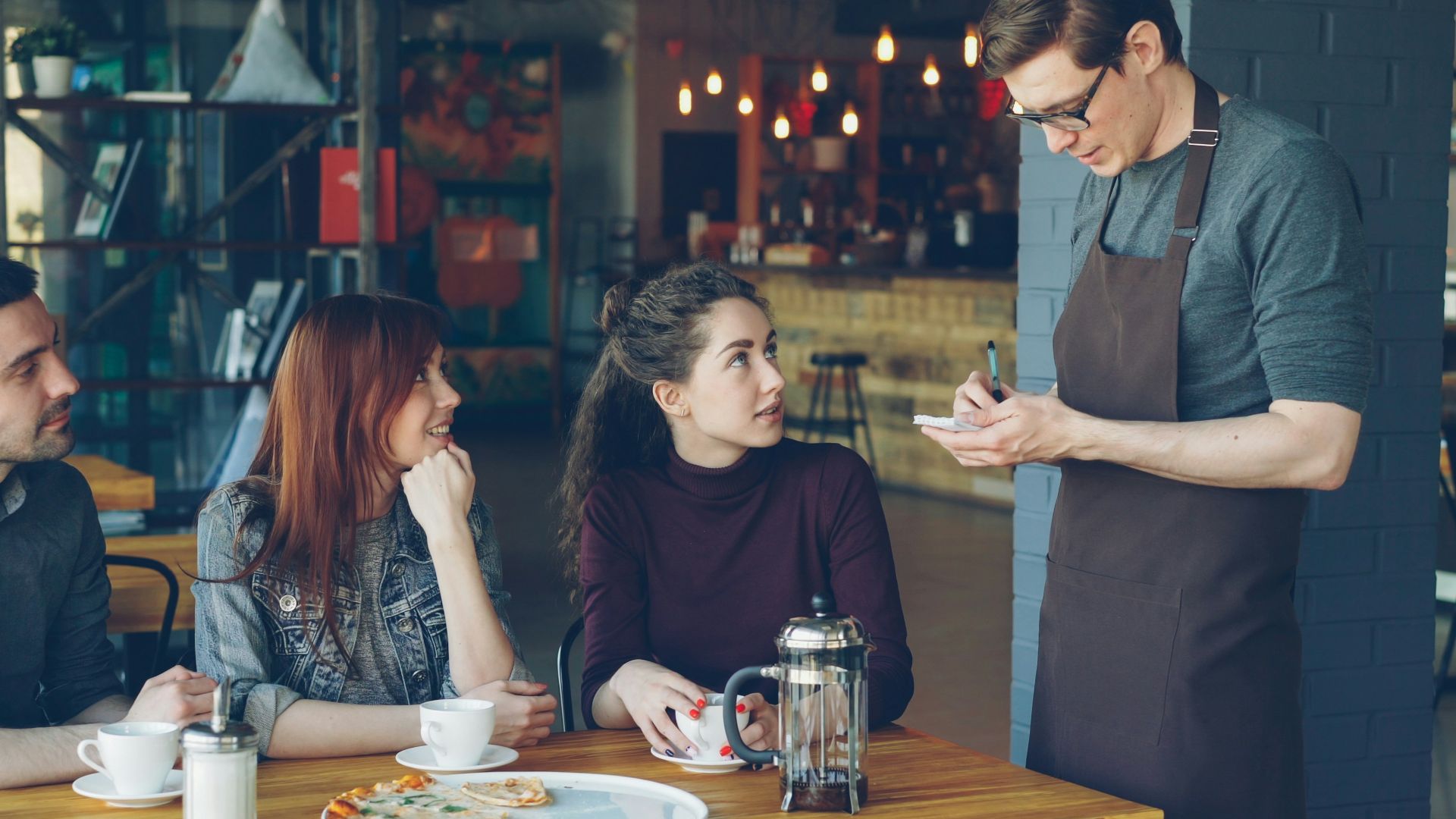 A waiter takes an order from customers at a cafe.