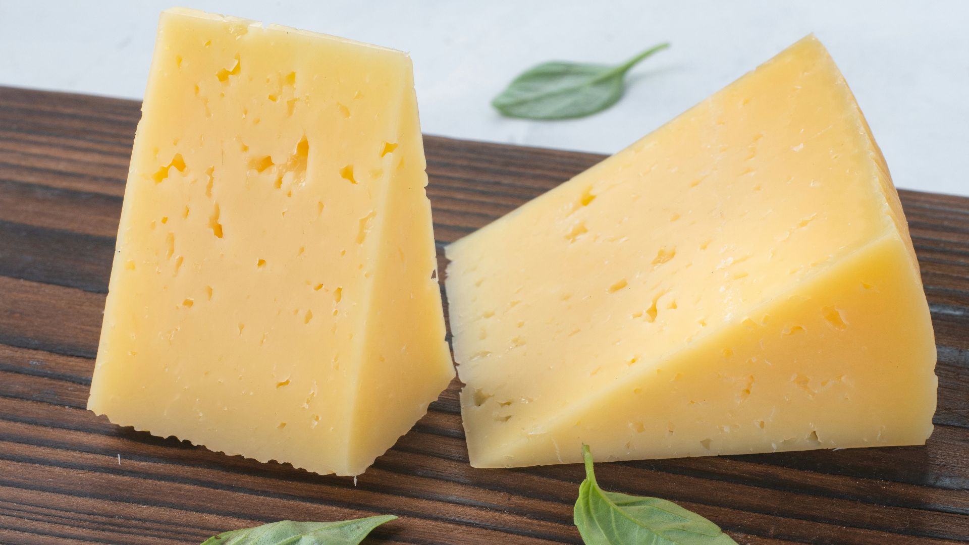 a couple of pieces of cheese sitting on top of a wooden cutting board
