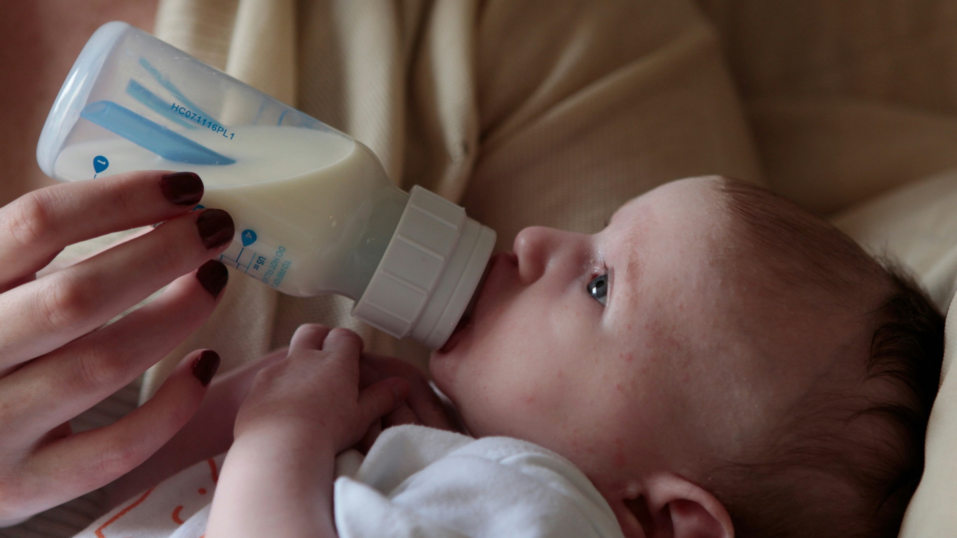 a woman feeding a baby with a bottle of milk