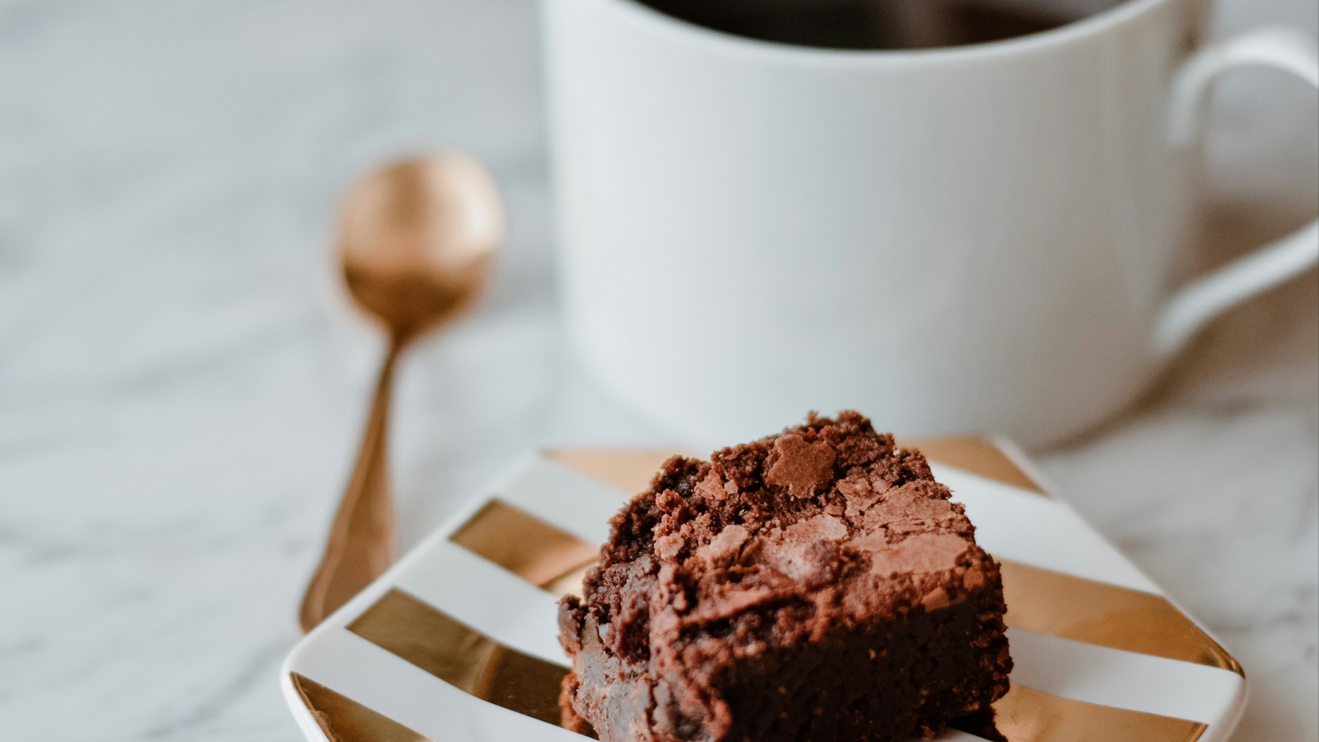 a piece of chocolate cake on a plate next to a cup of coffee