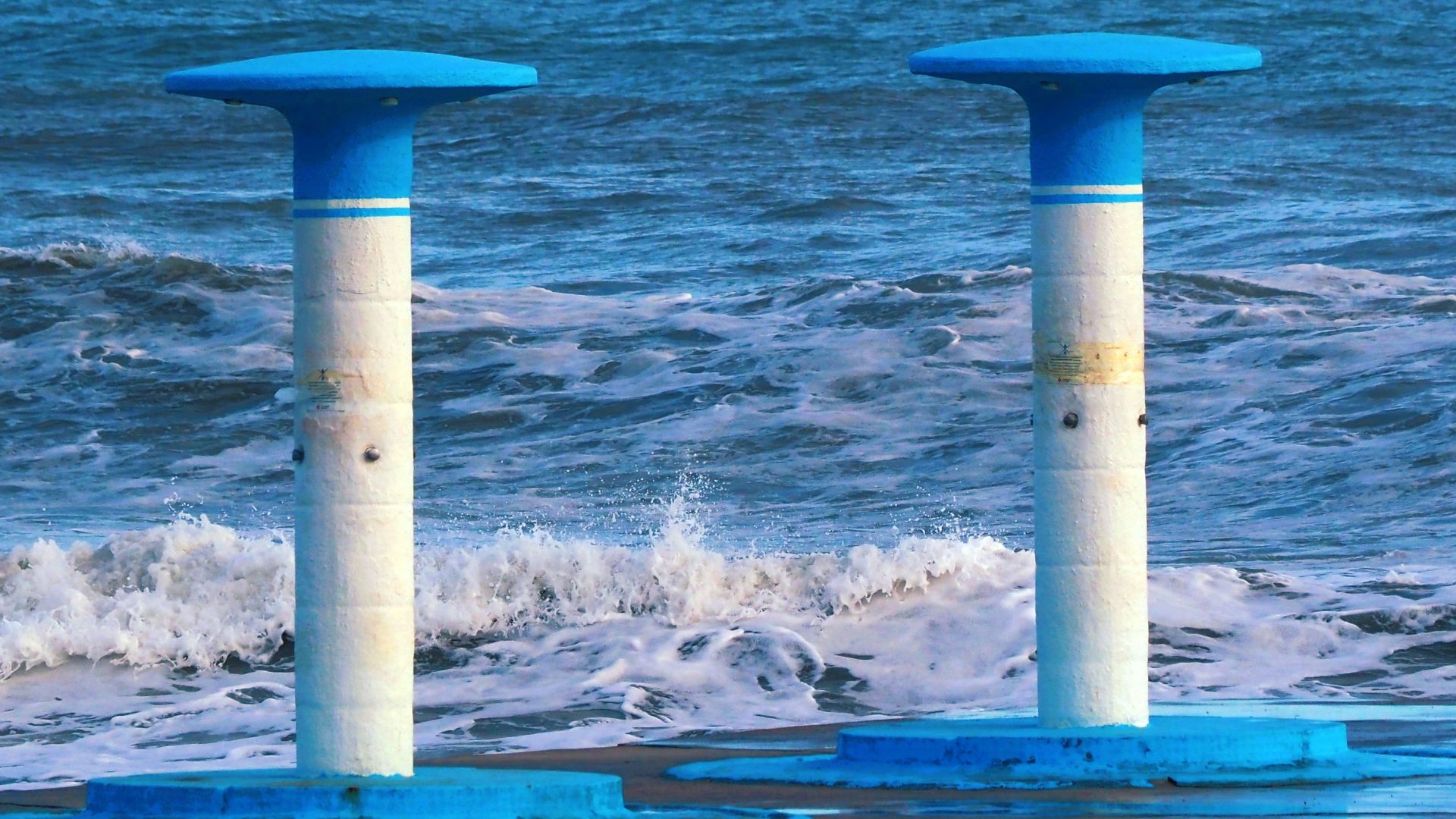 two blue and white poles sticking out of the ocean
