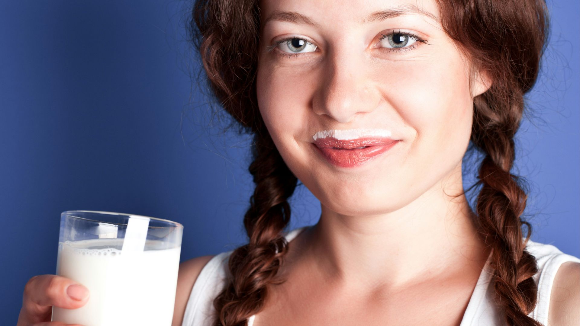 A woman is holding a glass of milk