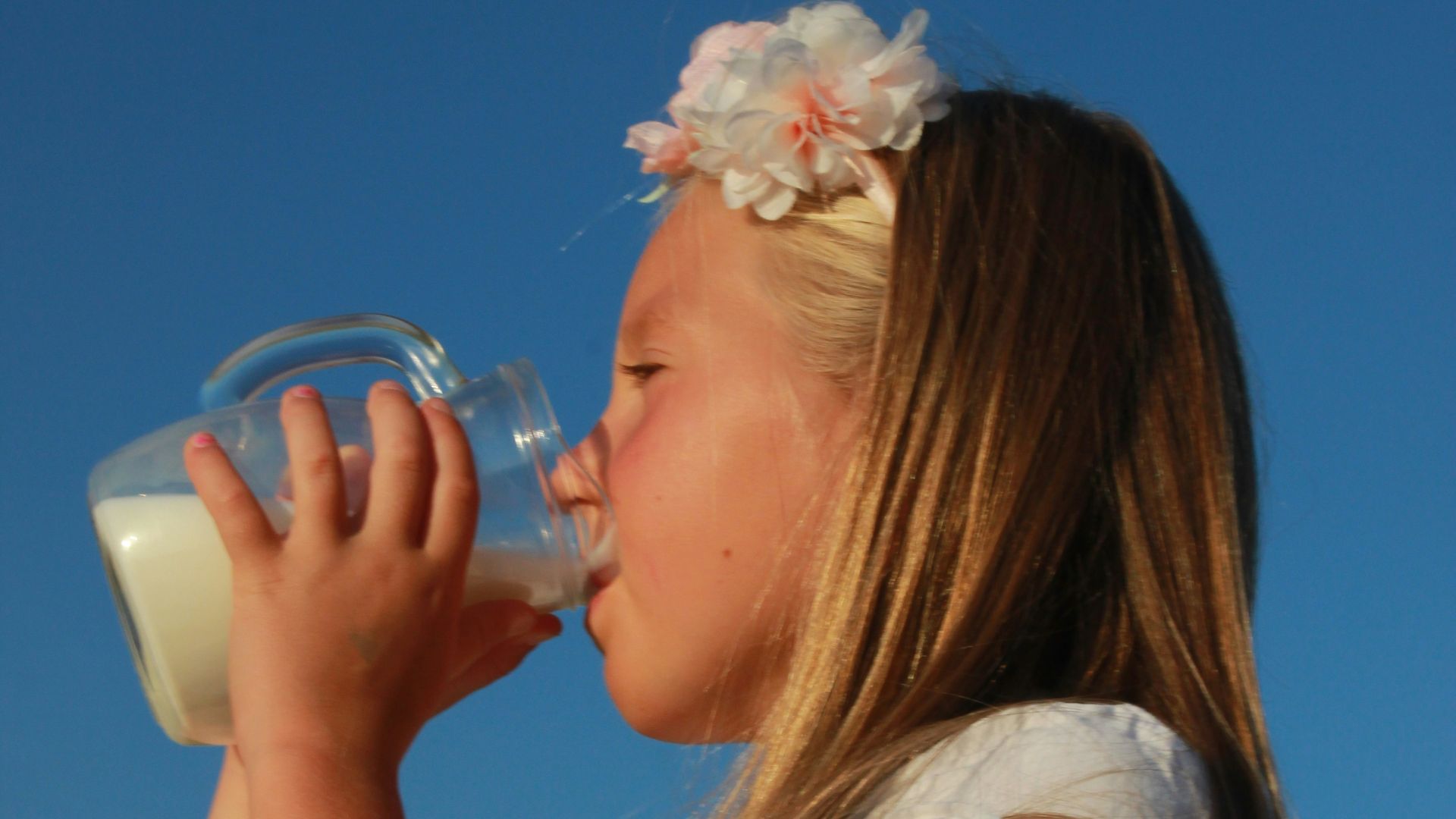 a young girl drinking from a bottle of milk