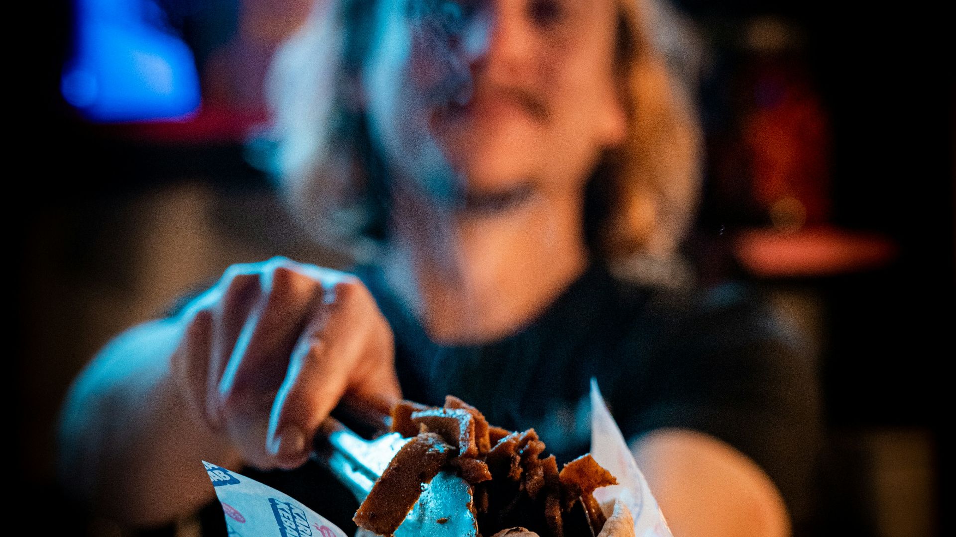 a woman holding a sandwich in front of a bar