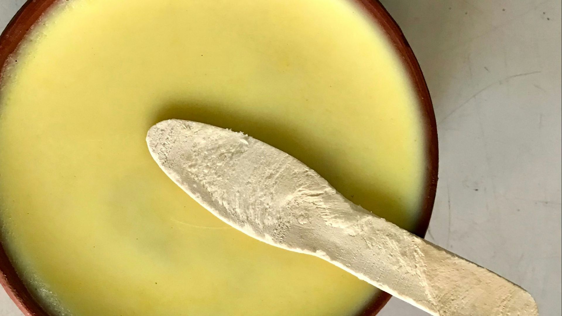 A spoon in a bowl with a liquid inside of it