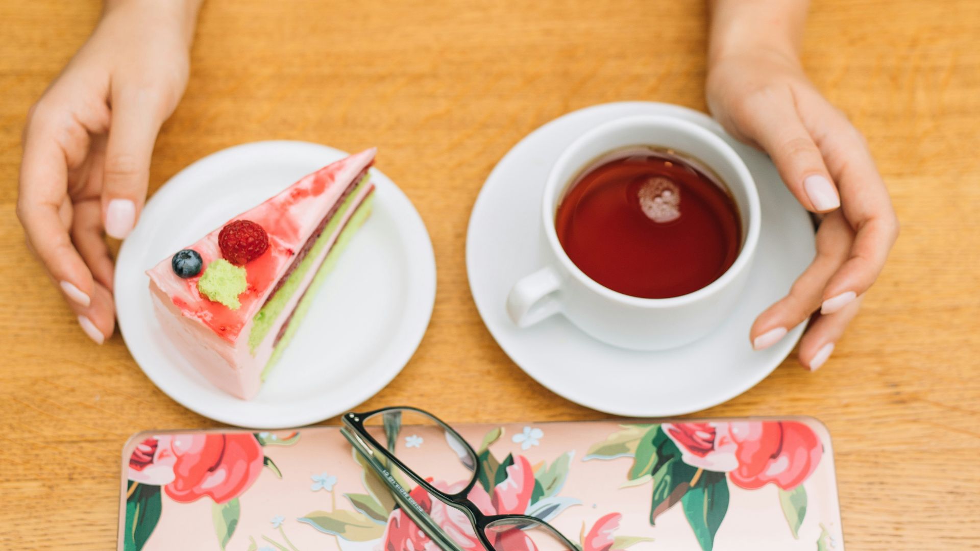 a woman sitting at a table with a piece of cake and a cup of tea