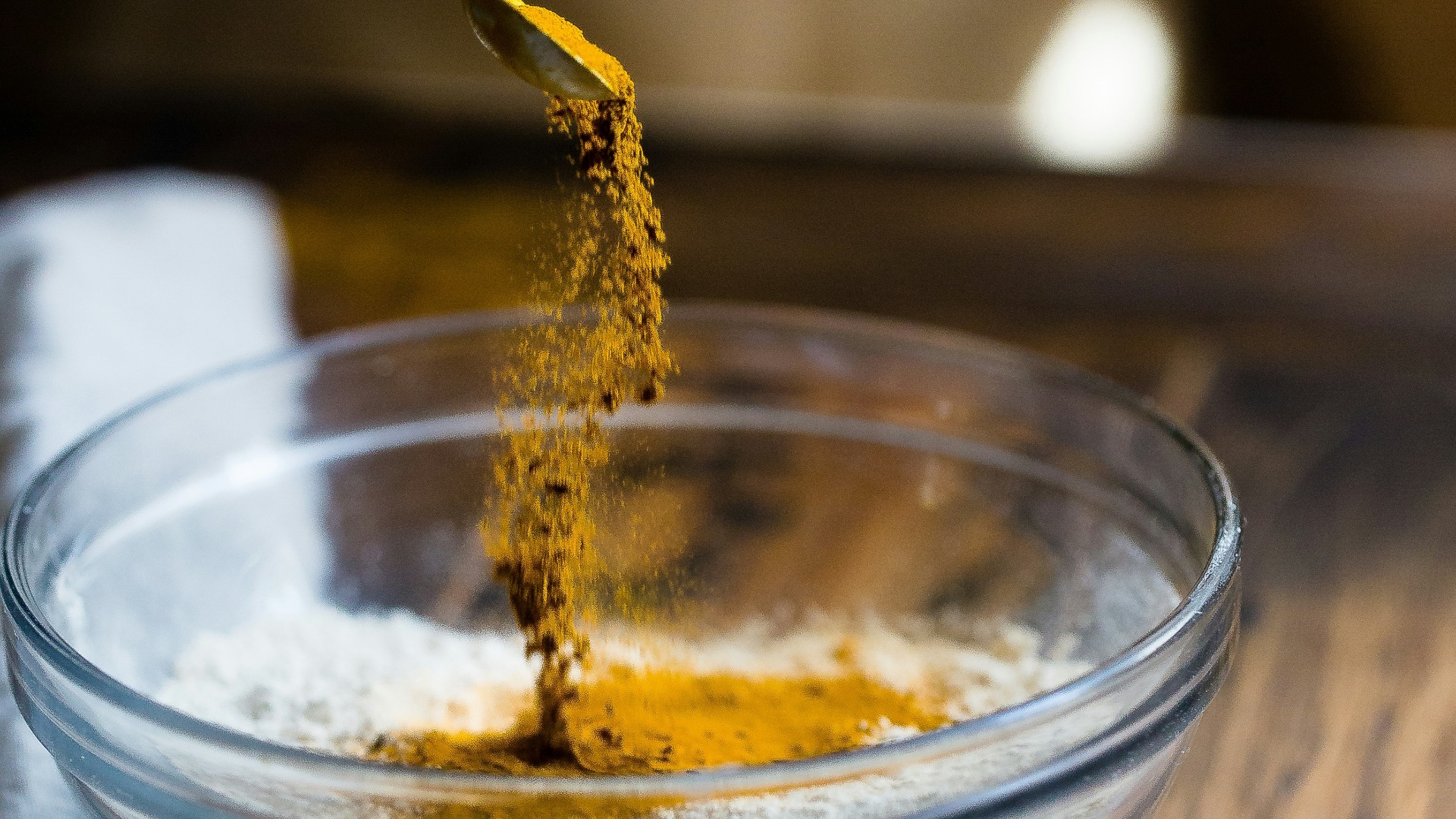 person pouring seasonings on clear glass bowl