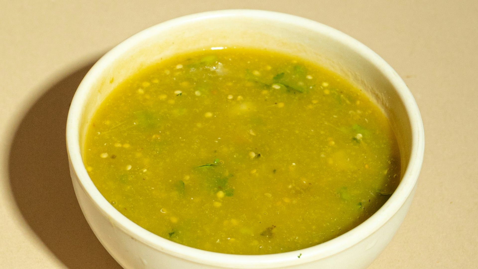 A white bowl filled with green soup on top of a table