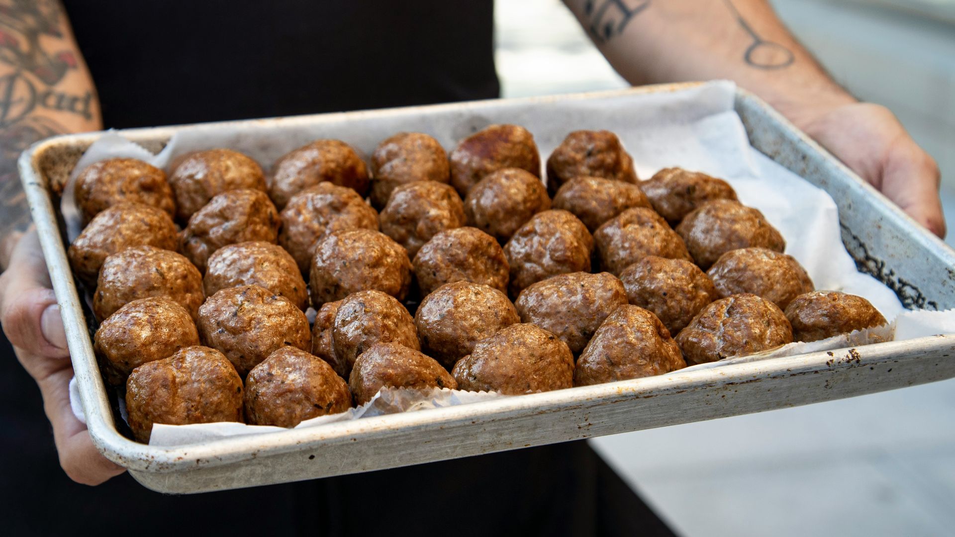 a person holding a tray of doughnuts on a sidewalk