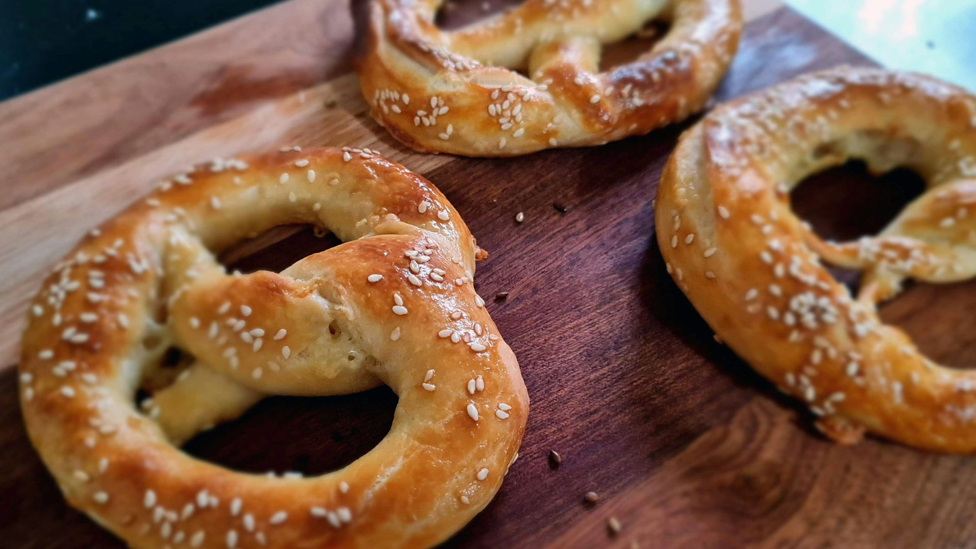 a wooden cutting board topped with three pretzels