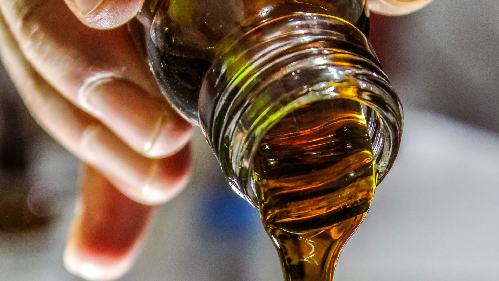person holding clear drinking glass with brown liquid