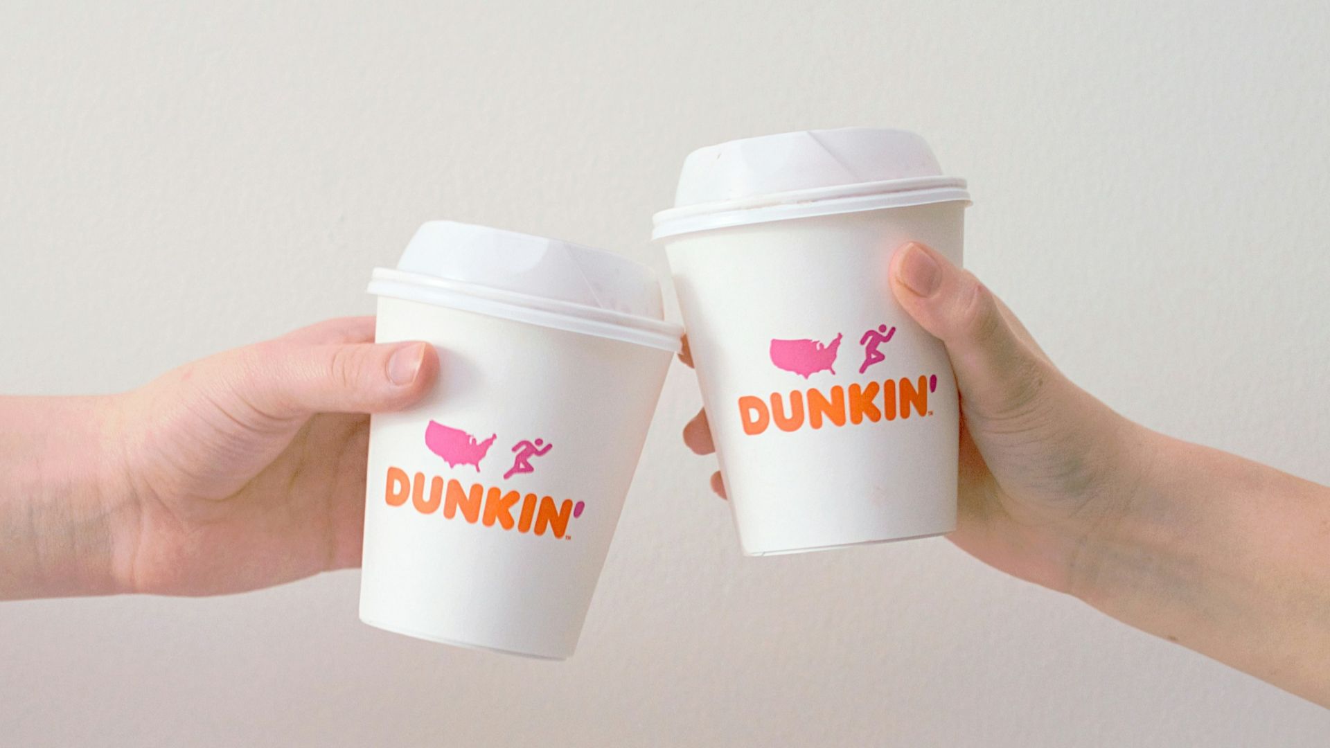 two people with white Dunkin' Donuts paper cups
